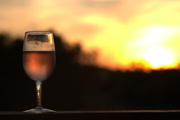glass of rose wine on sunset background