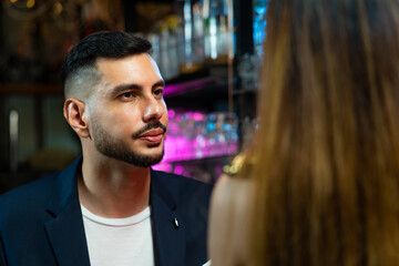 Asian woman talking to boyfriend with drinking alcoholic cocktail at bar counter in nightclub. Male bartender mixologist preparing mixed alcoholic drink with decorate cocktail glass at bar counter