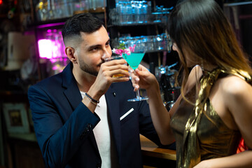 Asian woman talking to boyfriend with drinking alcoholic cocktail at bar counter in nightclub. Male bartender mixologist preparing mixed alcoholic drink with decorate cocktail glass at bar counter