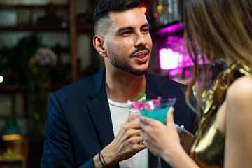 Asian woman talking to boyfriend with drinking alcoholic cocktail at bar counter in nightclub. Male bartender mixologist preparing mixed alcoholic drink with decorate cocktail glass at bar counter