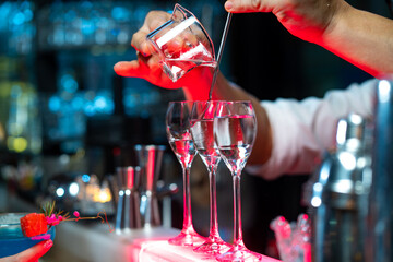 Bartender preparing tasty mixed alcoholic drink with ice cube in decorated cocktail glass on bar counter for customer in nightclub. Celebration party, nightlife business and alcohol addiction concept