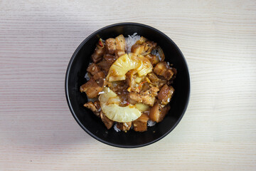 Rice bowl topped with pork adobo and pineapple.