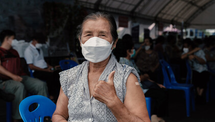 senior woman has gone to vaccinate coronavirus covid19 shoulder with bandage showing thumbs up at...