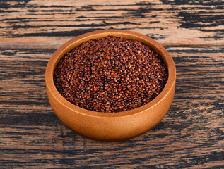 Red quinoa grains in a wooden bowl isolated on wooden background