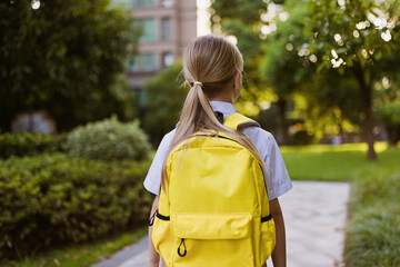 Back to school. Little girl with yellow backpack from elementary school outdoor. Kid going learn new things 1th september after end Coronavirus covid-19 quarantine and self isolation 