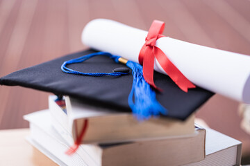 Cropped photo of a university graduation hat mortarboard and diploma degree certificate on the table