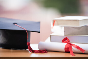 Cropped photo of a university graduation hat mortarboard and diploma degree certificate on the table