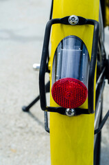 Closeup red lamp of yellow bicycle still in public garden