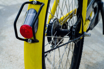 Closeup red lamp of yellow bicycle still in public garden