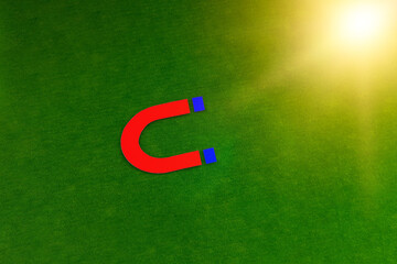 A magnet on a green background. The concept of attraction, energy.