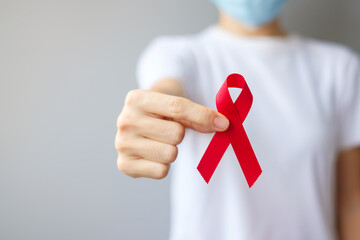 Hand holding Red Ribbon for December World Aids Day (acquired immune deficiency syndrome), multiple...