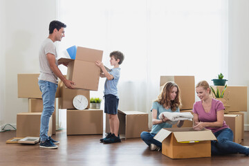 Parents and children sit floor Unpacking During move new home.