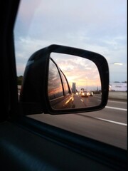 Sunset in the rearview mirror on the highway