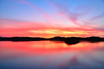 Fototapeta na wymiar 水面に反射する夕焼けの空、夏の湖の夕景