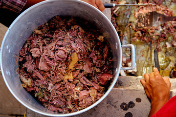 Close up of a pot with traditional Mexican lamb barbecue style meat with agave leaves on the background