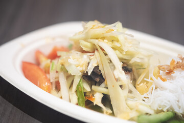 Papaya salad with crab served on a white paper dish