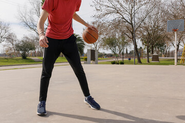 Young man's body dribbling a basketball. No face is visible.