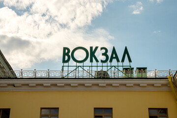 Sign: Station - in Russian, on the roof of the Main Railway Station of the city on a sunny summer day.