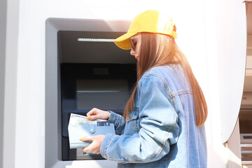 Young woman using ATM outdoors