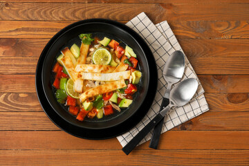 Bowl of tasty Sopa de Lima soup on wooden background