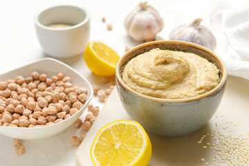 Bowl with tasty hummus and ingredients on table
