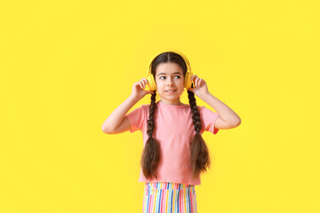 Cute little girl listening to music on color background