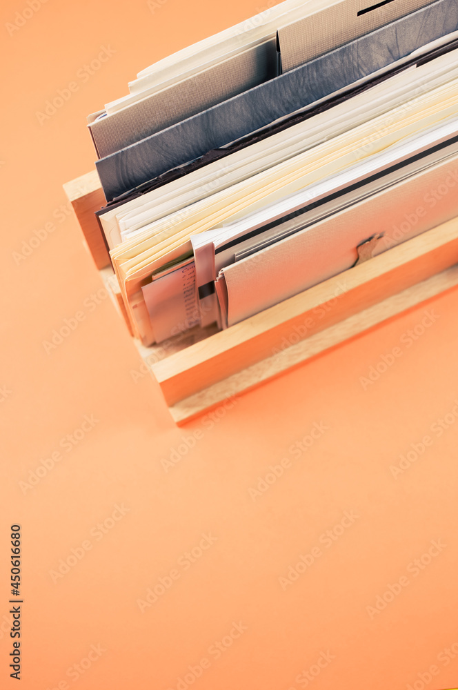 Sticker vertical shot of filled documents on a wooden shelf isolated on an orange background