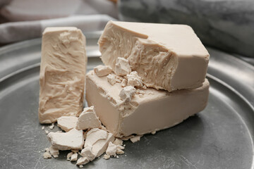 Tray with fresh yeast briquettes on table