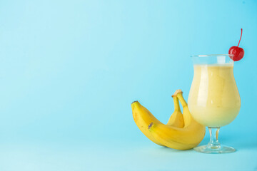 Fototapeta na wymiar Glass of tasty banana daiquiri cocktail and fruits on color background