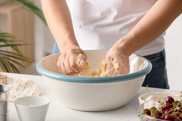 Woman preparing dough for cherry pie at table, closeup