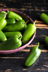 Plate with green jalapeno peppers on dark wooden background, closeup