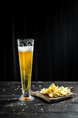 beer into a tall glass with Shredded Squid with pepper, fish snacks on wooden background. Beer brewery concept. Beer background