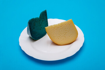 Pieces of cheese on a white plate on a blue background