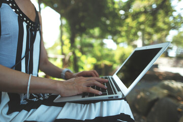 屋外でラップトップを使用する人物の手元クローズアップ 緑背景ぼかし