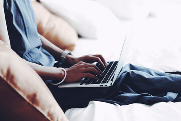 室内でベッドに座ってラップトップを使用する女性