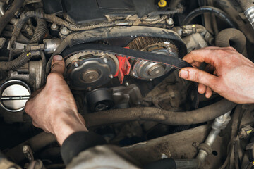 Auto mechanic changes the timing belt in the car, close-up - obrazy, fototapety, plakaty