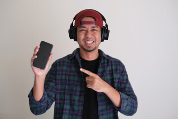 Cool Asian man smiling and pointing finger to his mobile phone