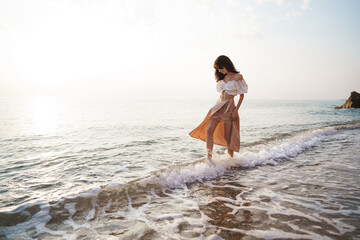Obraz premium Lonely young woman walks on the seashore at sunset
