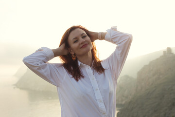 Portrait of red hear young woman dressing in white shirt poising over sky