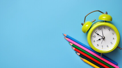 Bright school background with pencils and an alarm clock