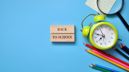 Bright school background with pencils and an alarm clock and the inscription: 