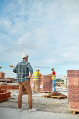 Foreman inspecting the work of two young builders