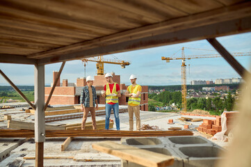 Three workers in hardhats having a conversation on the construction site