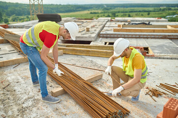 Experienced focused builders in cotton gloves selecting rebars