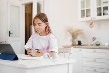 Homeschooled little young girl student having online class using digital tablet