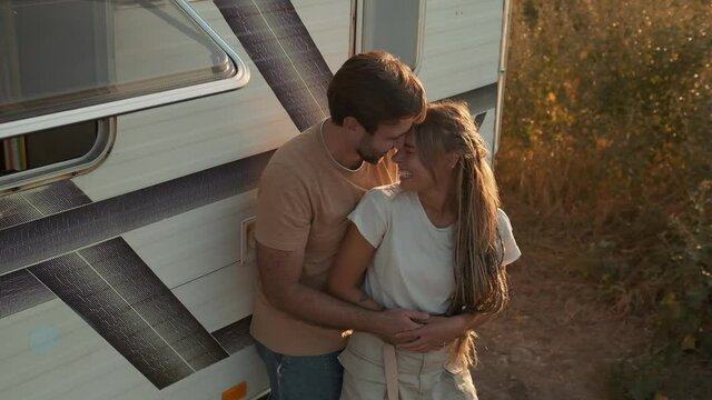 A top view of a happy couple man and woman dating standing near caravan trailer outside