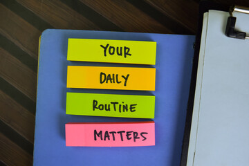 Your Daily Routine Matters write on sticky notes isolated on Wooden Table.