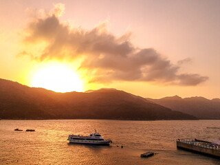 A photo of the sunset sky, mountains, and boat