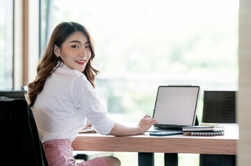 Beautiful businesswoman smiling and looking at camera while sitting at her desk office.