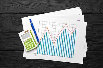 Business graphs paper and calculator on table